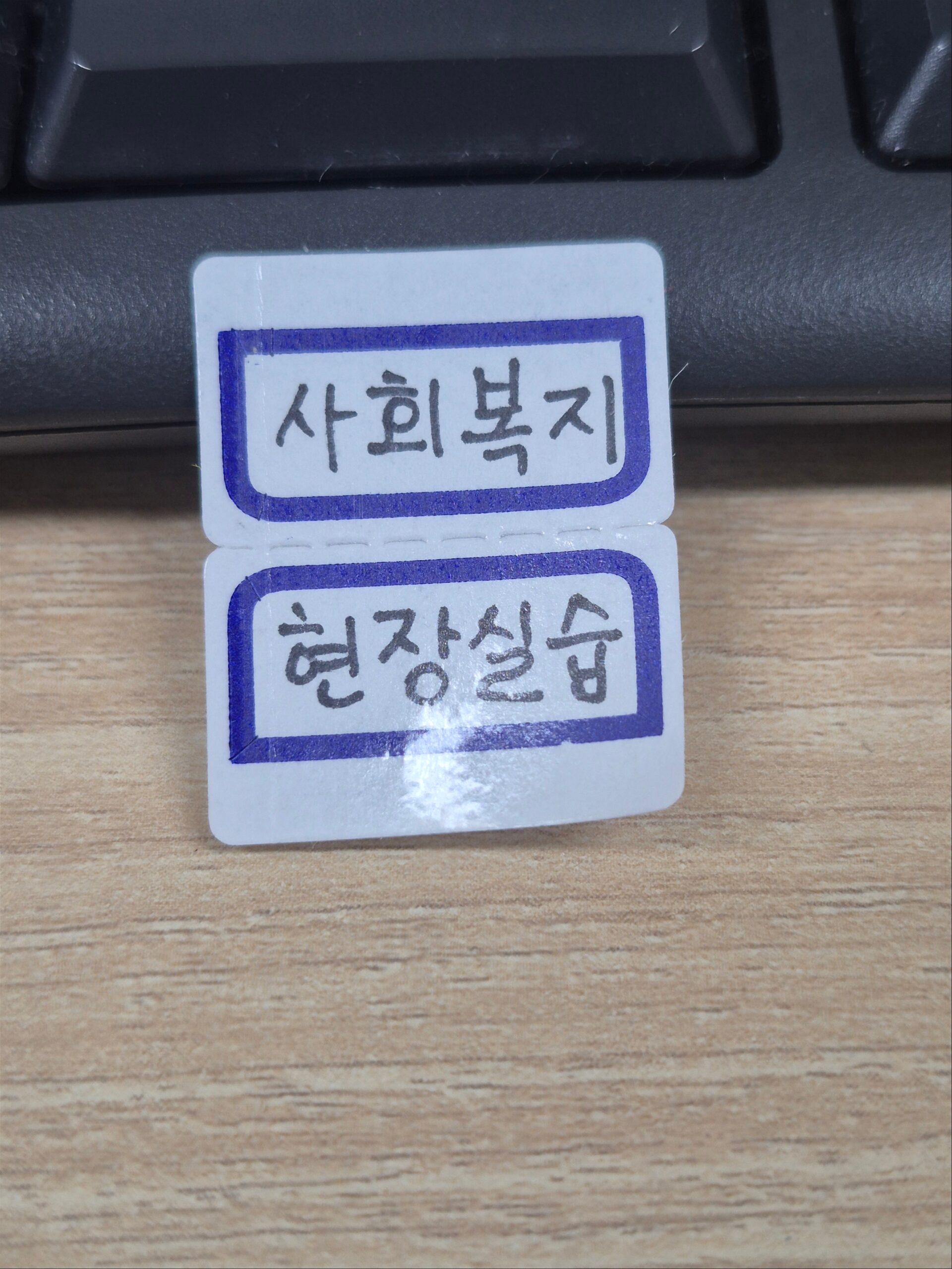 키보드와 책상 위에 '사회복지 현장실습'이라고 손글씨로 적힌 흰색 라벨 스티커