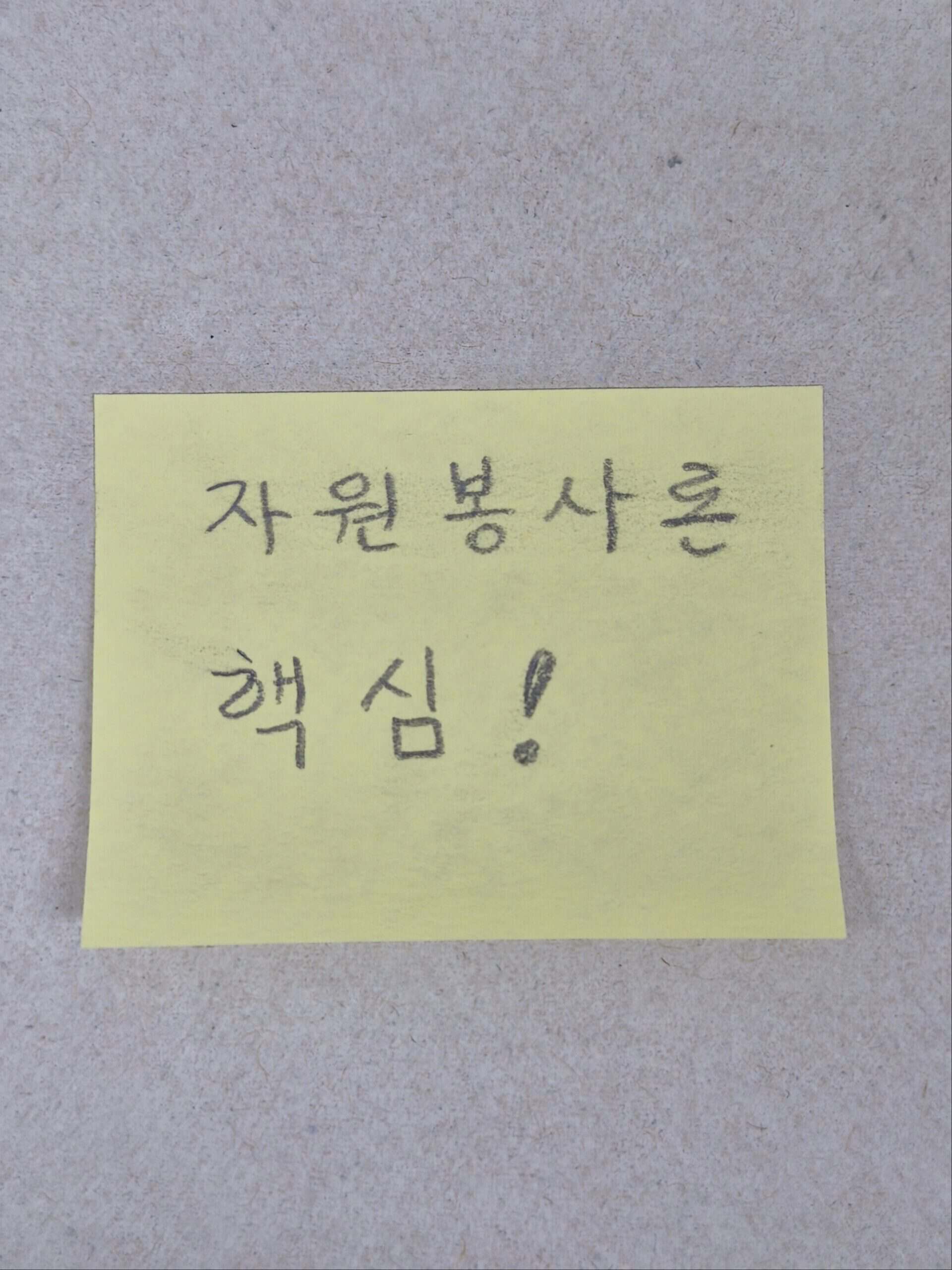 크라프트 종이 바탕에 '자원봉사론 핵심!'이라고 손글씨로 적힌 노란색 메모지 이미지