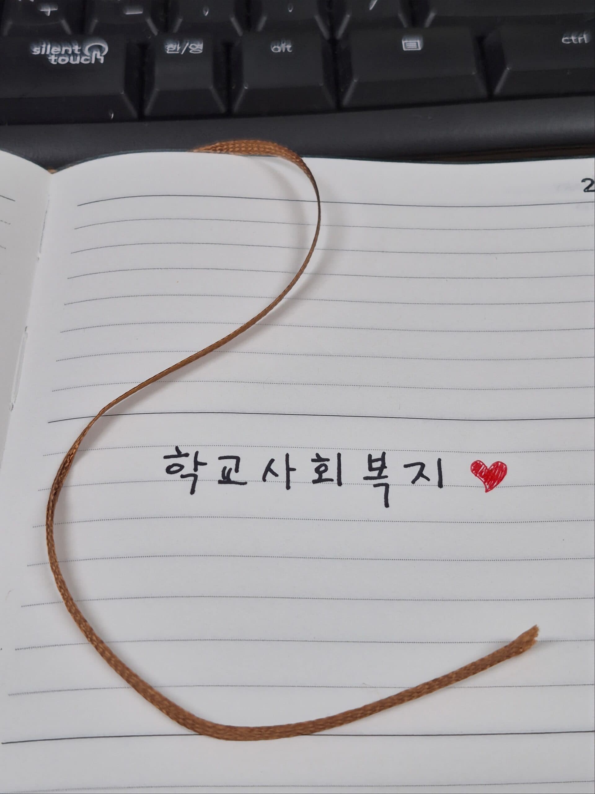 노트에 손글씨로 쓴 학교사회복지 메모와 키보드